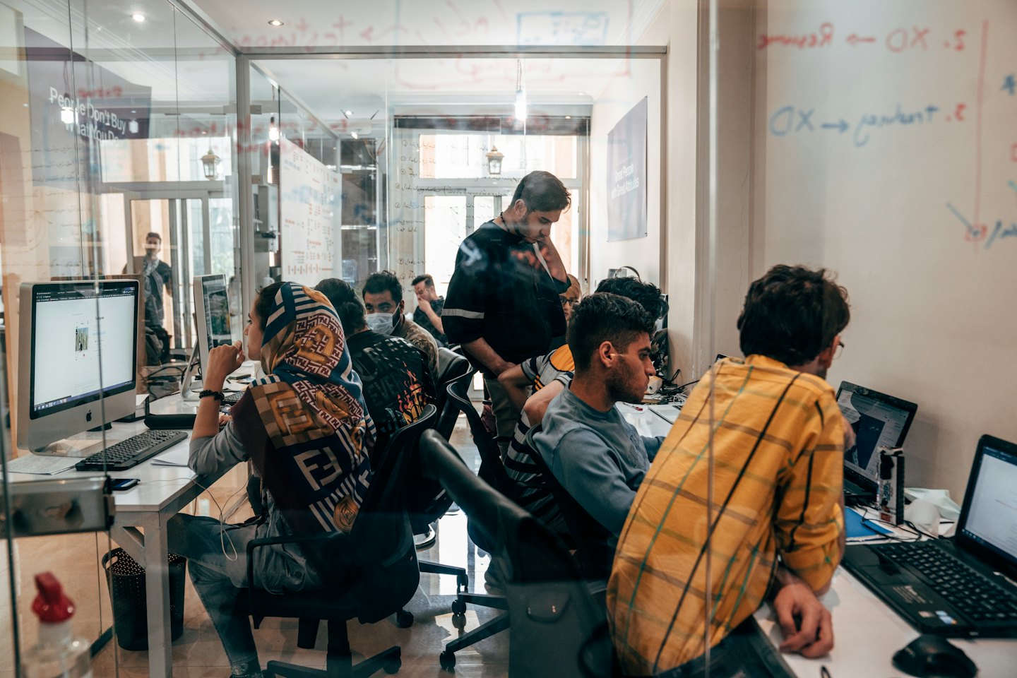Professionals collaborate on laptops in a bright, modern office space.