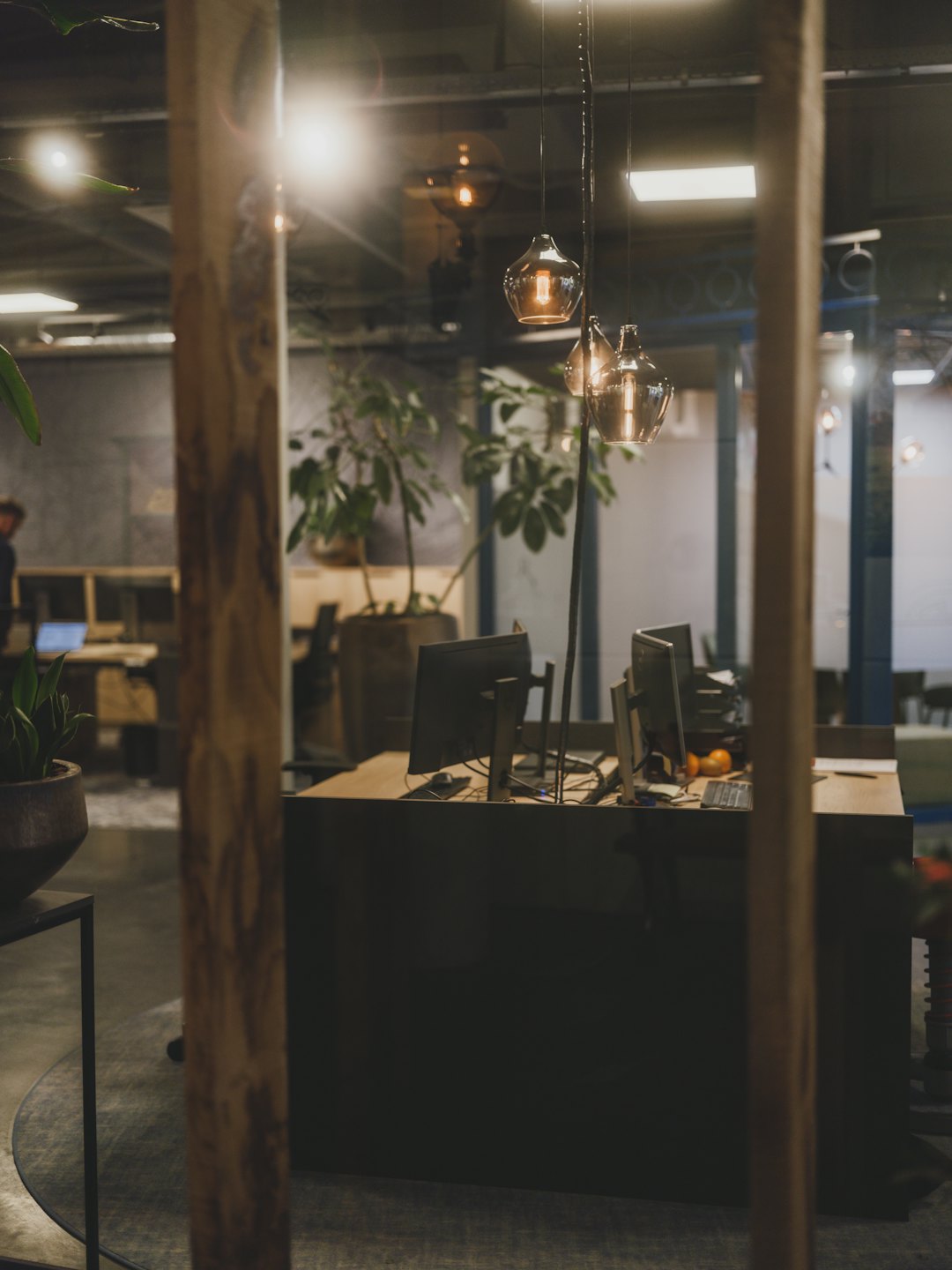 Modern office workstation with dual monitors and plants.